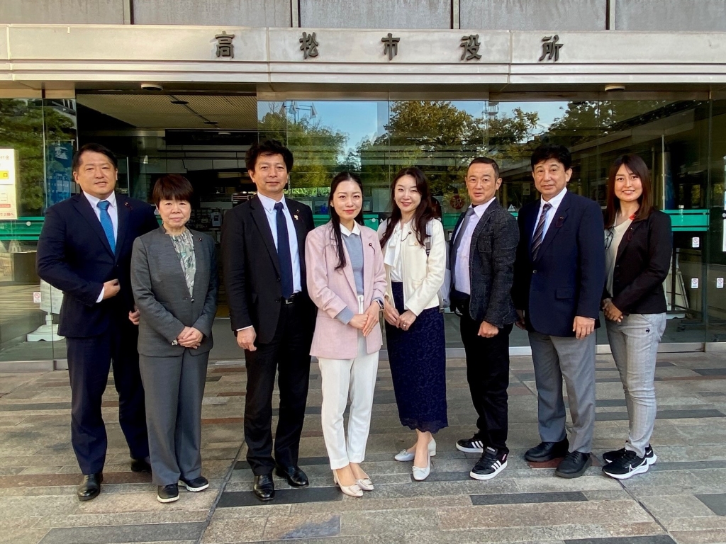 写真：高松市役所玄関前での区民福祉委員会委員8人の集合写真