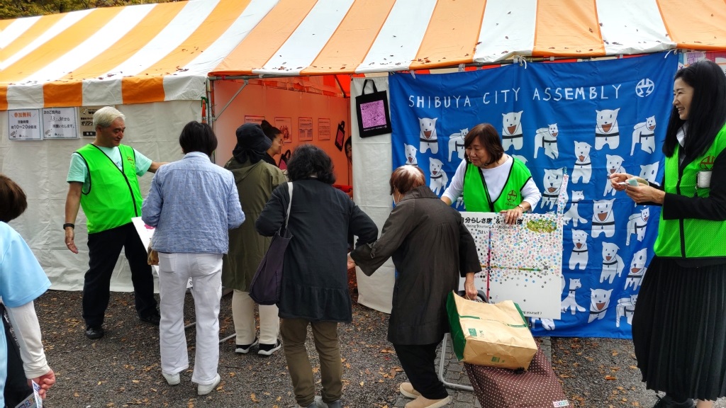 写真：区議会テントの前で、議員が来場者を案内している様子