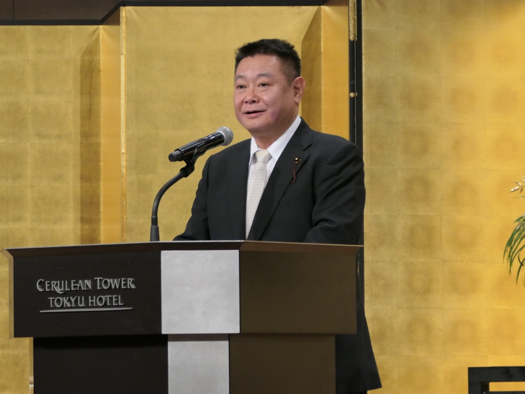 写真：壇上にて挨拶をする　ひとつやなぎ　なおひろ　議長