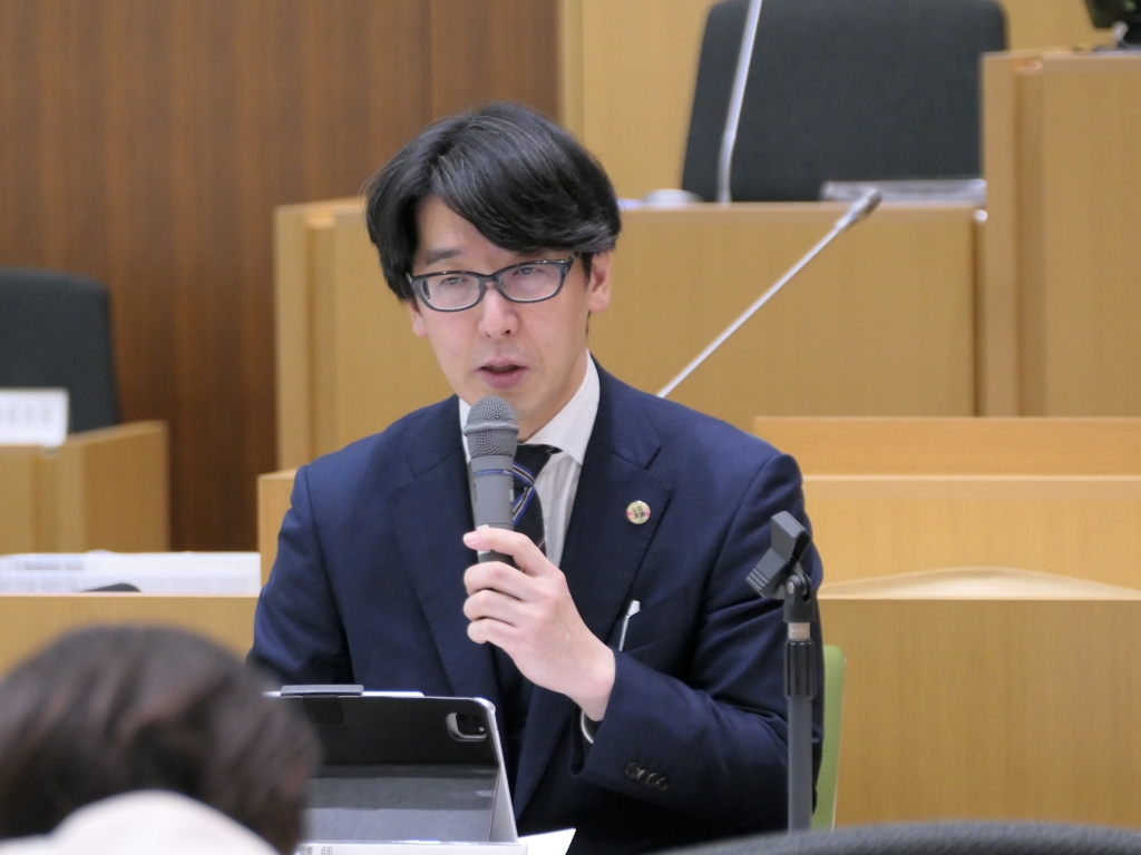 写真：議場で席に着いて話す　講師の　みやはら まさかず氏