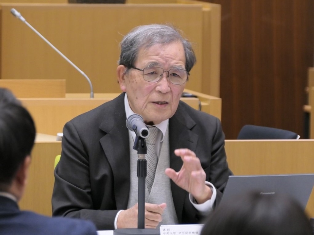 写真：議場で席に着いて話す　講師の　やまだ ただし氏